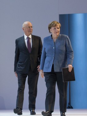 Klaus Schwab and German Chancellor Angela Merkel arrive for a plenary session at last yearâ€™s WEF in Davos