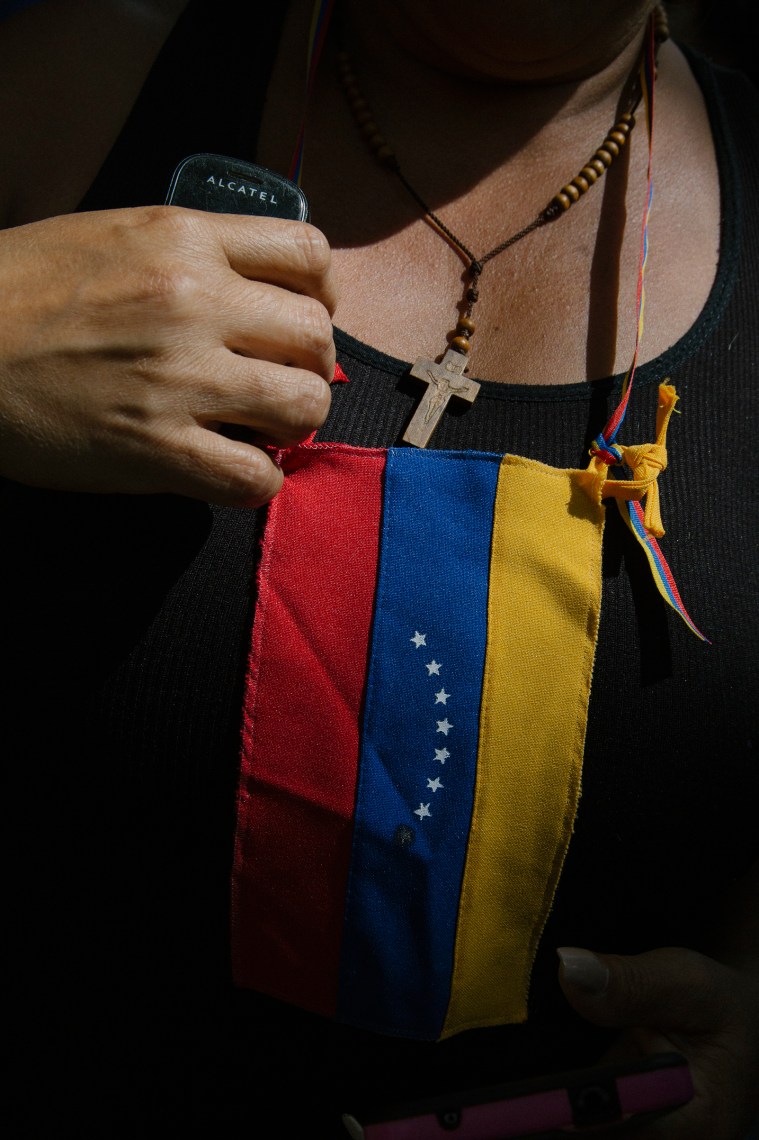 A woman fixes a flag on her chest during a news conference by GuaidÃ³ at the Bolivar Square of Chacao in Caracas on Jan. 25, 2019.