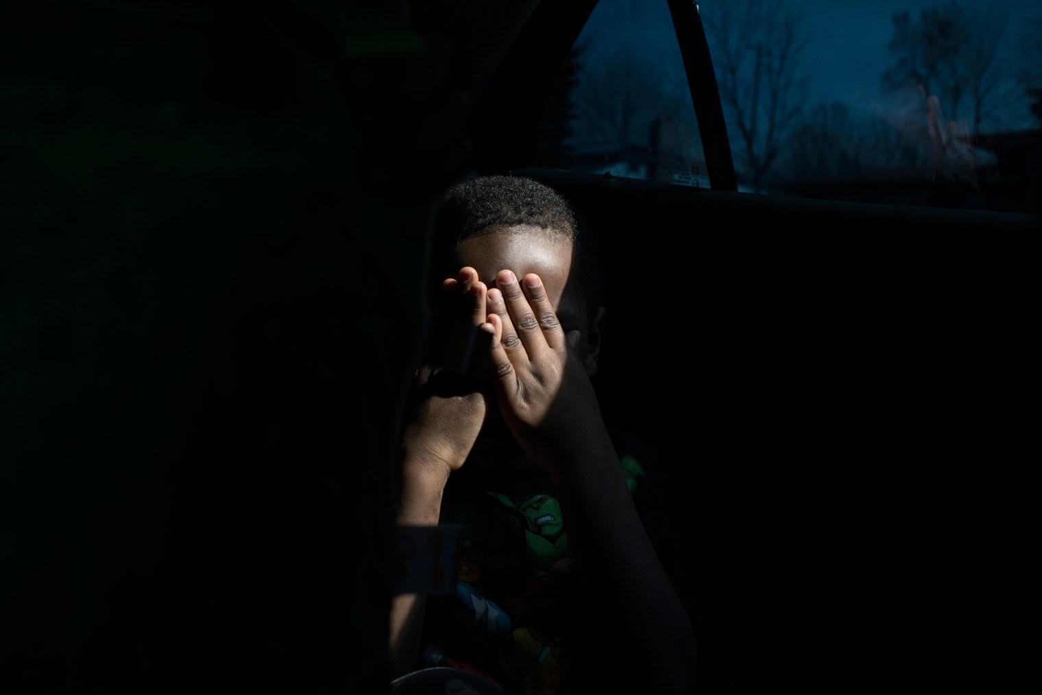 Sincere hides his face from the camera after getting picked up from school.