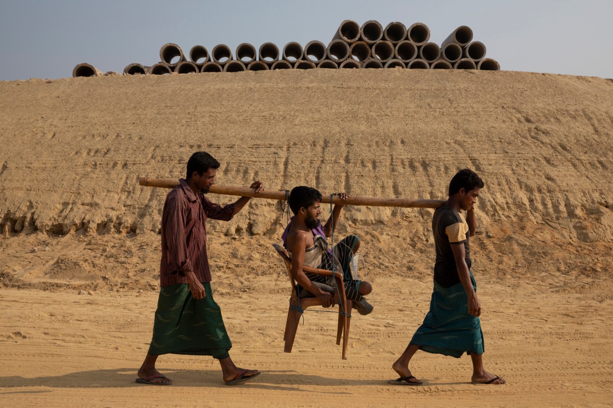 Shamsul Alam, who suffers from a chronic intestinal illness, is carried to a health clinic through the Camp 20 Extension construction zone. He is helped by a brother, Salam, left, and a nephew, Yunus.