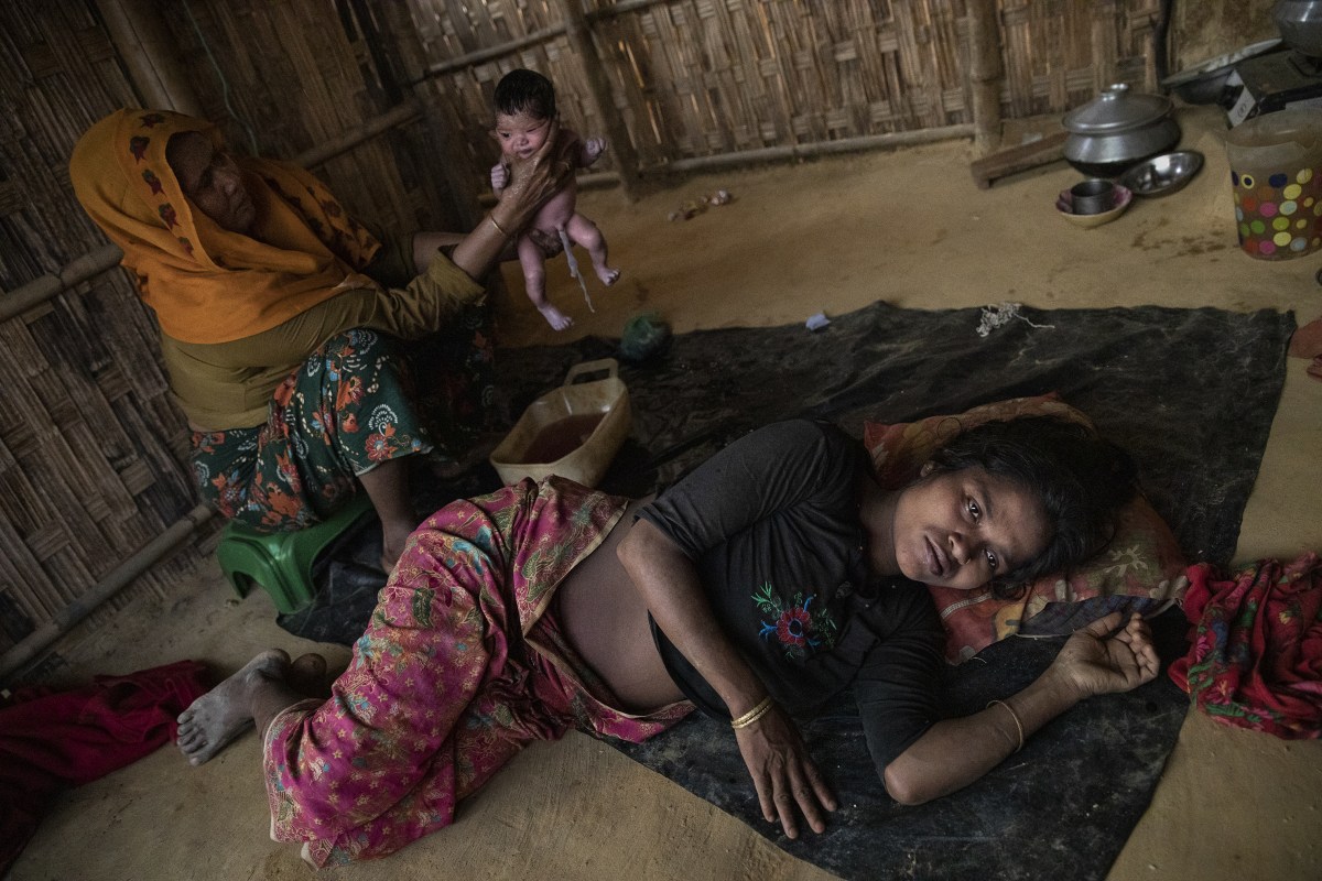 A midwife, Nur Nahar, holds Yasmin, a girl delivered moments earlier to Janoka Bibi, 20, in Kutupalong camp in April. The girlâ€™s father abandoned the family.