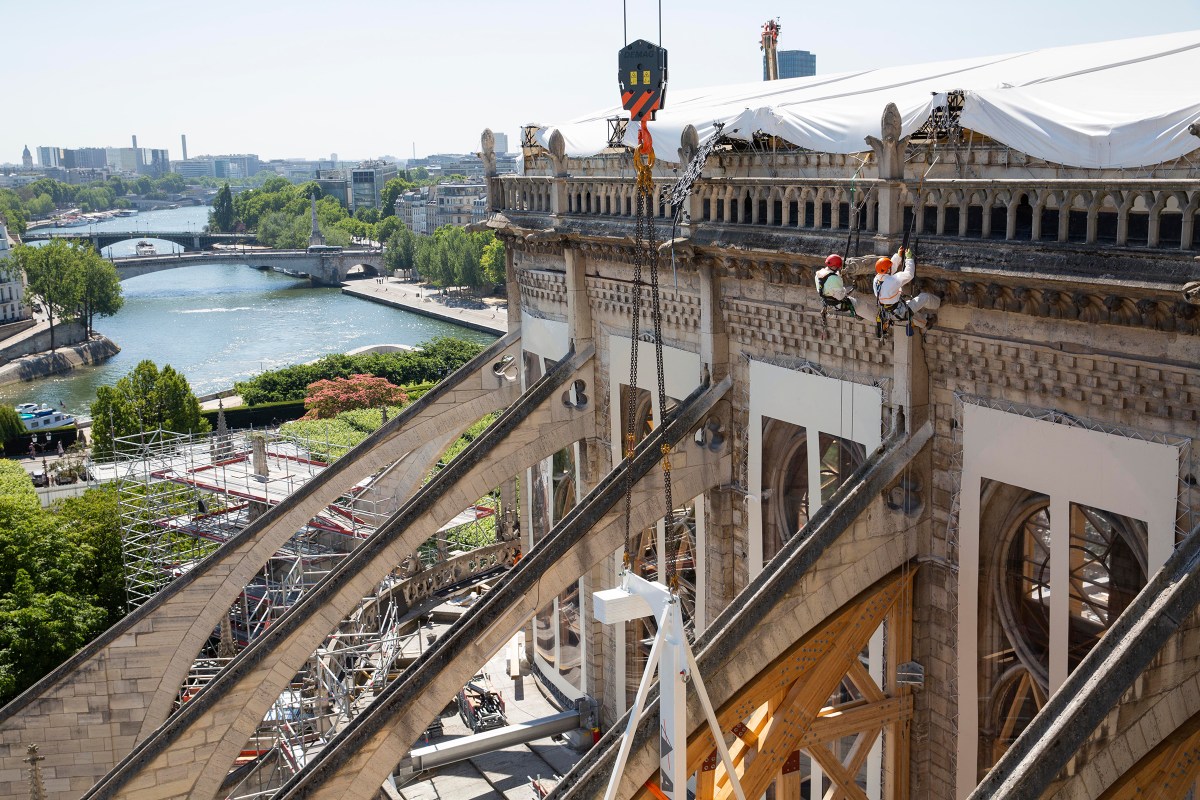 Two workers rappel down the side of the Cathedral as wooden arches are installed to support the flying buttresses on July 2.