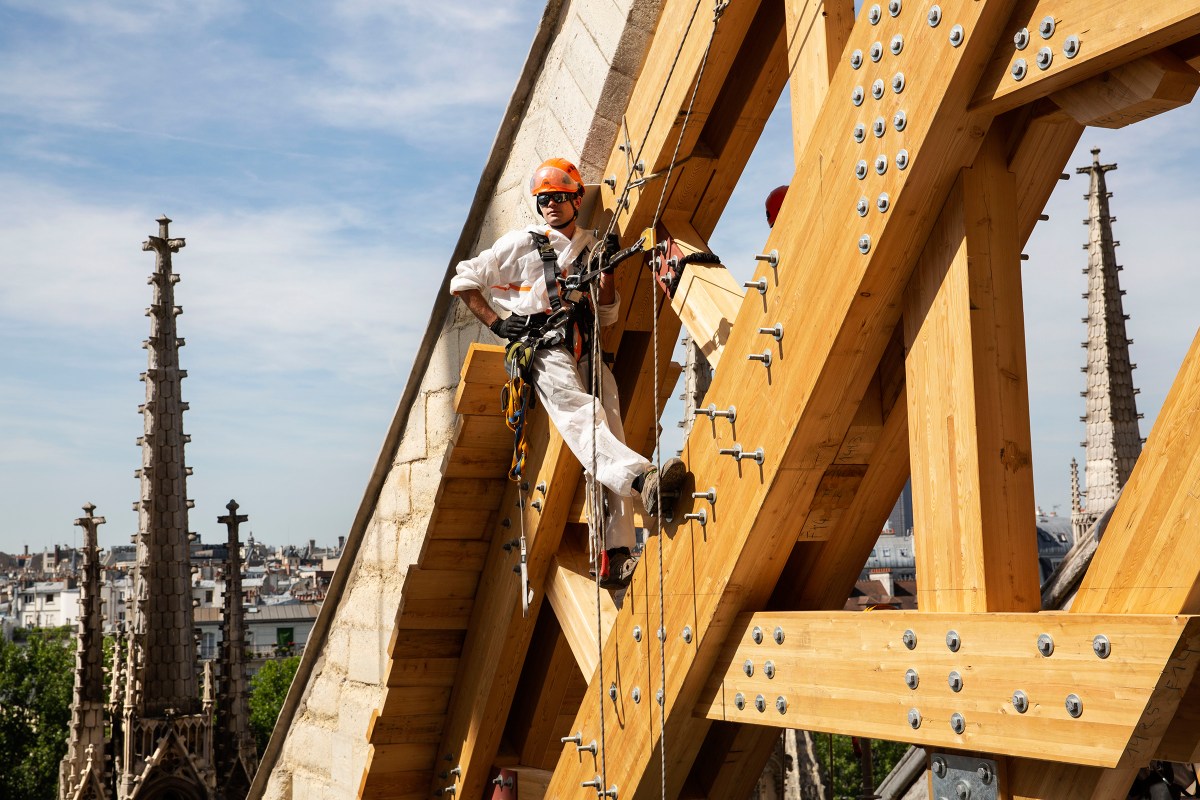 A rope-access technician installs a wooden arch to support a flying buttress on July 22, 2019.