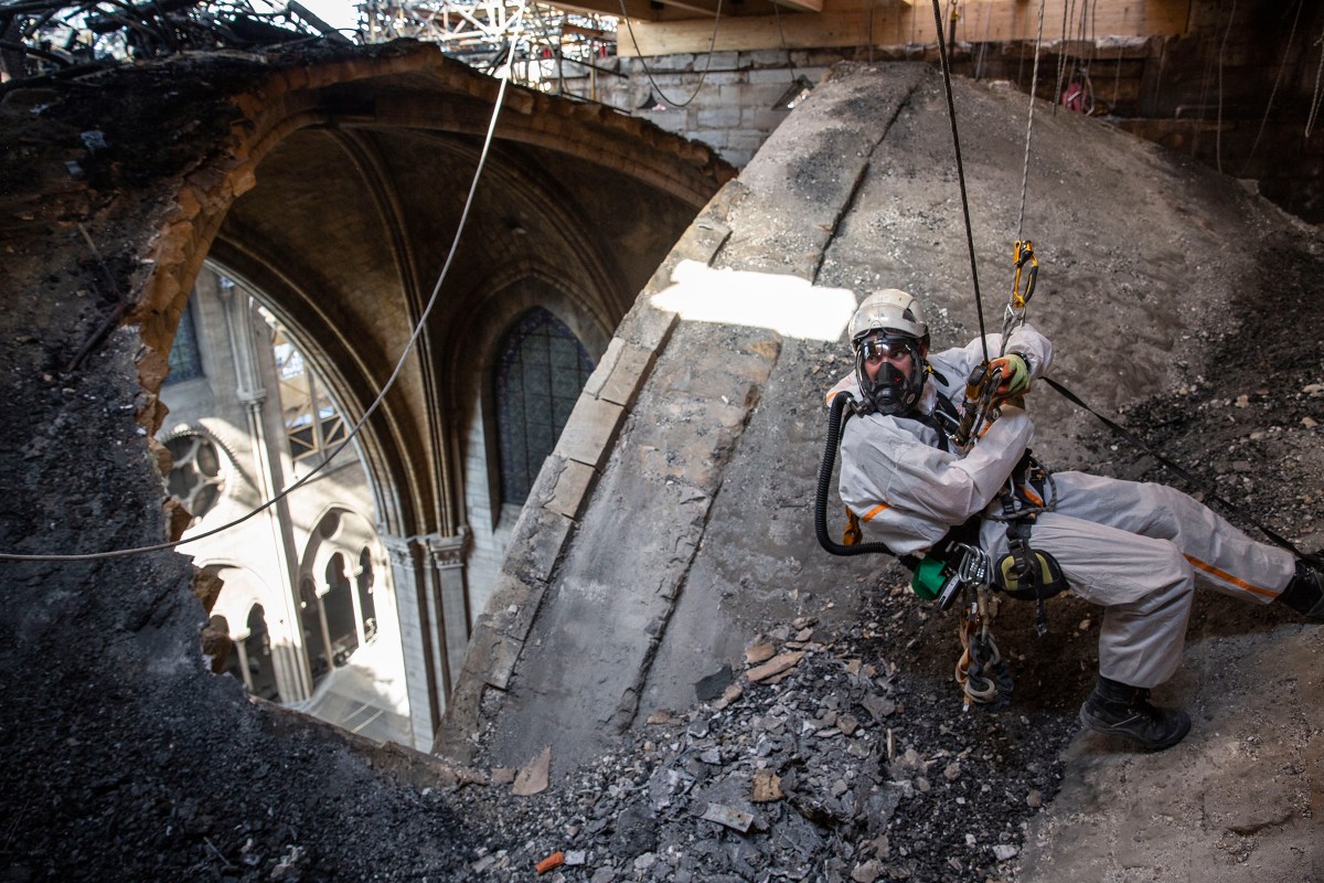 A worker near an open part of the roof. Some sections of the cathedral have since been exposed to rainfall and high temperatures that France has experienced.