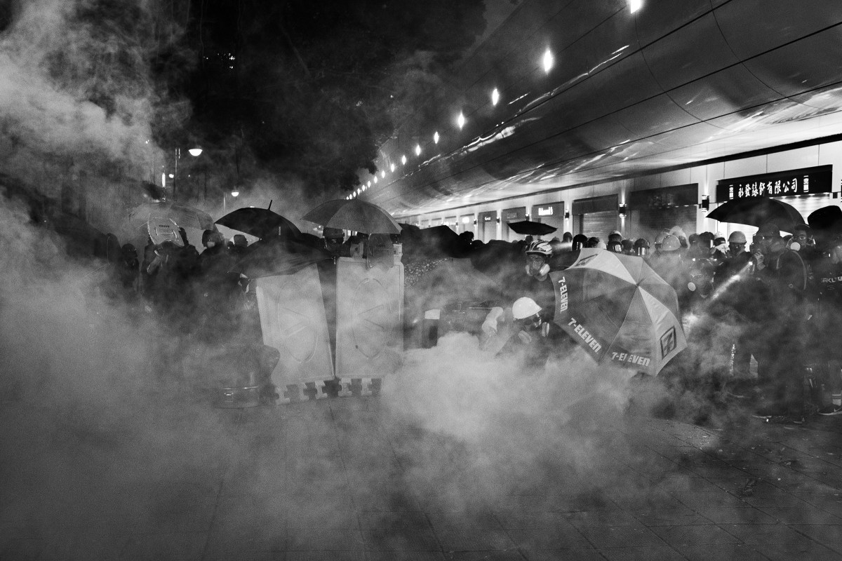 Protesters are tear-gassed by riot police near the Tsim Sha Tsui police station in Kowloon, Hong Kong, on Aug. 11.