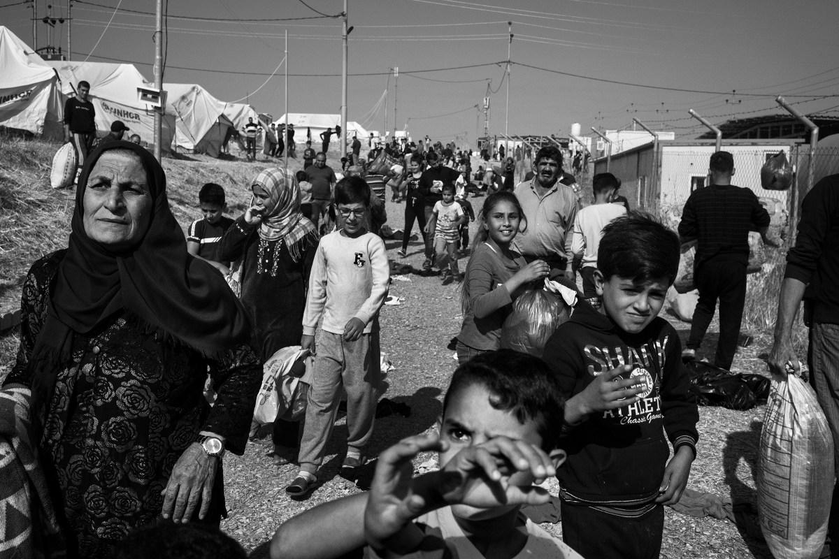 Syrian Kurdish refugees gather to receive winter clothes during a distribution inside the Bardarash camp on Oct. 31.